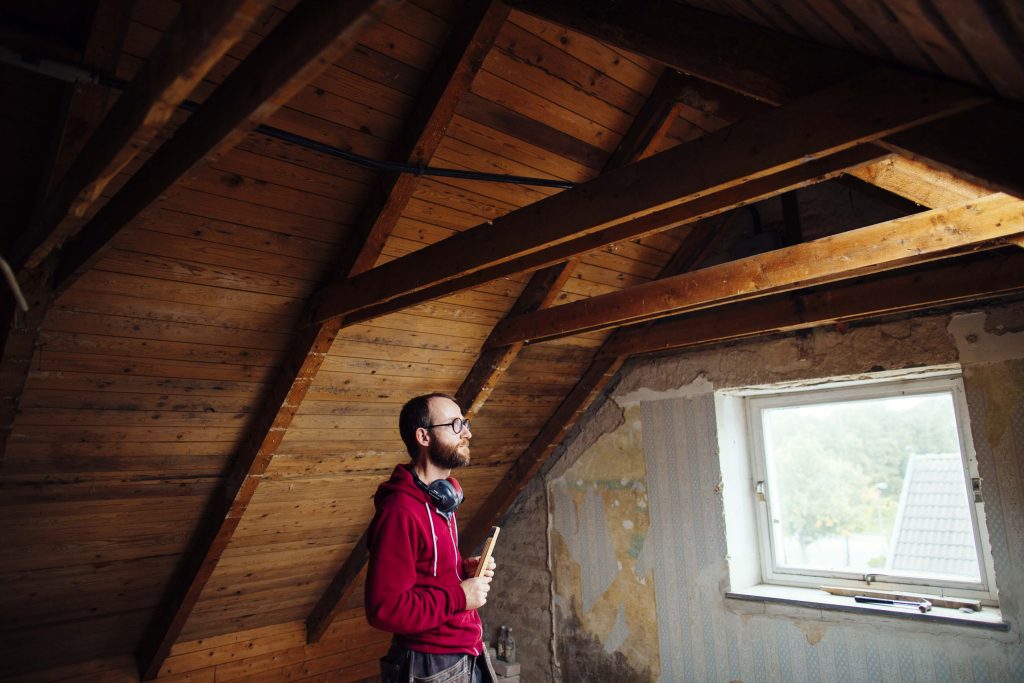 Inspecting a home's roof and windows after a storm to check for weather damage as part of a home watch service.