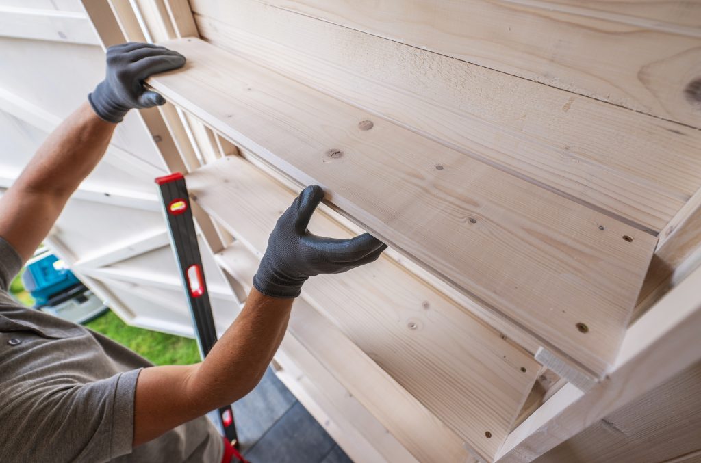 A handyman installing custom wooden shelves in a modern living room.